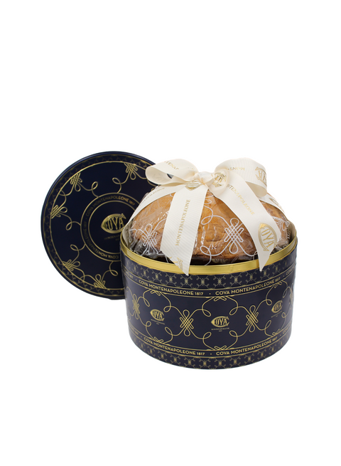 A traditional Italian Panettone cake packaged in a round blue tin box with ornate gold designs, topped with a white ribbon bow.